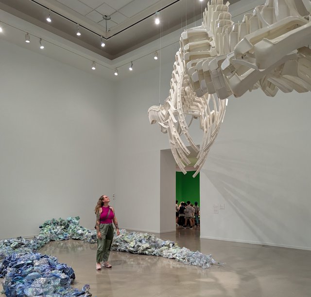 whale skeleton made of plastic lawn chairs with Stacey looking up at it